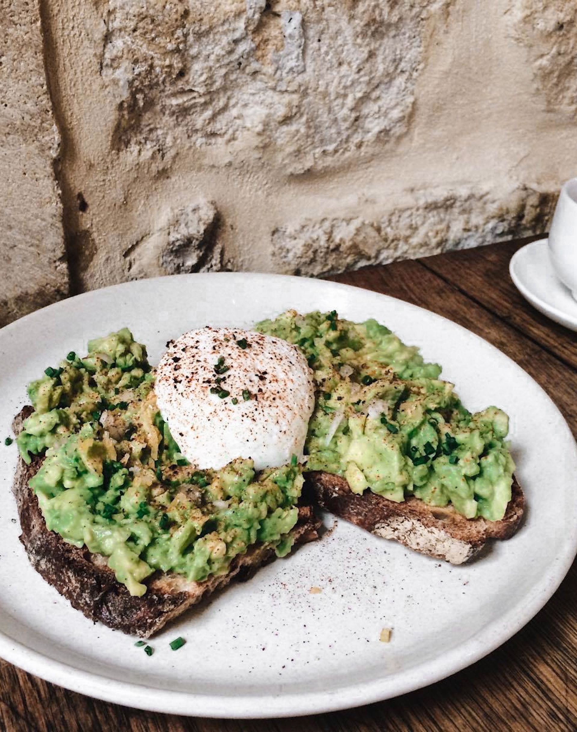Toast with avocado and a poached egg on a stoneware plate