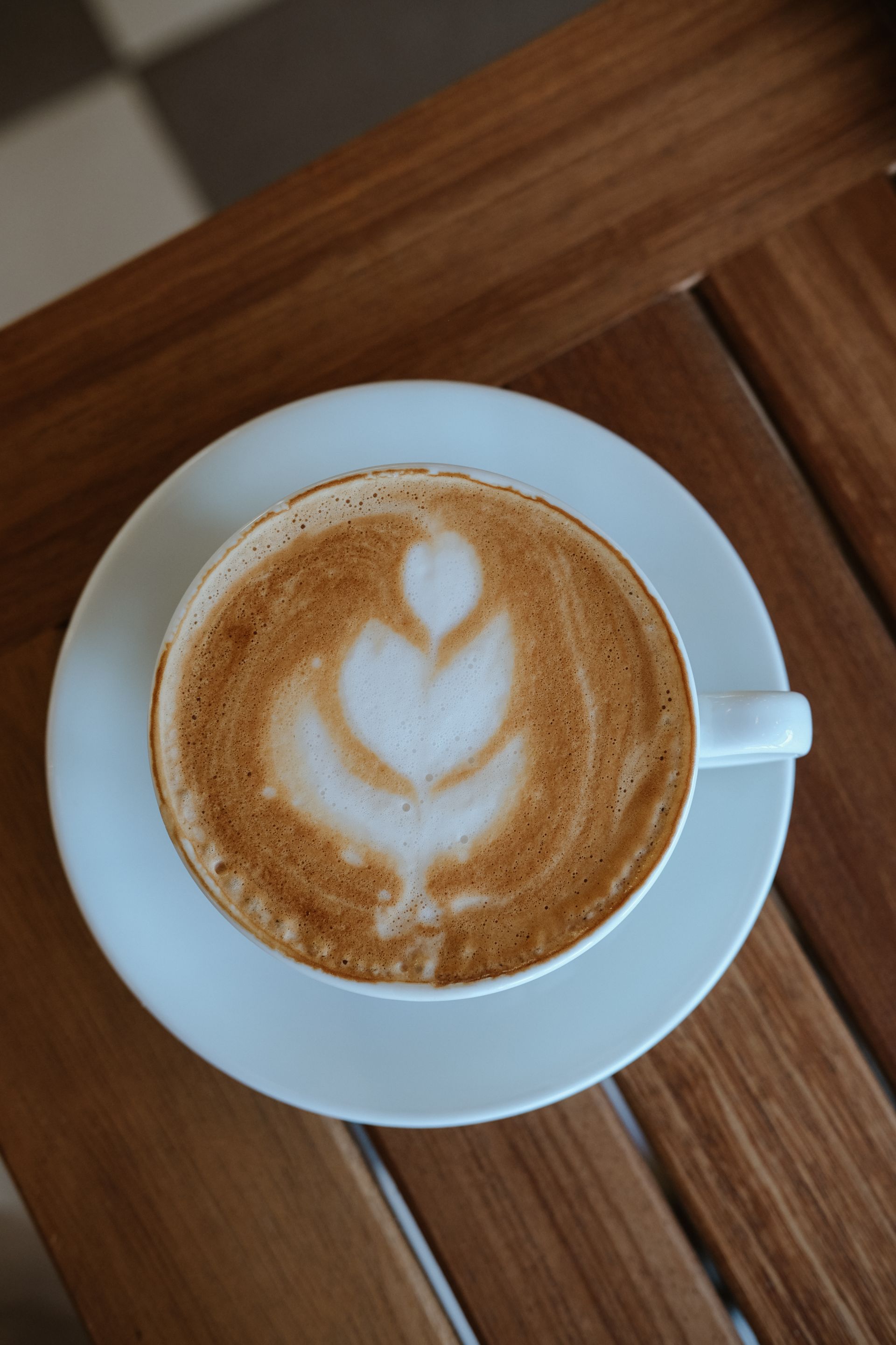 Latte art in a white ceramic cup on a timber table